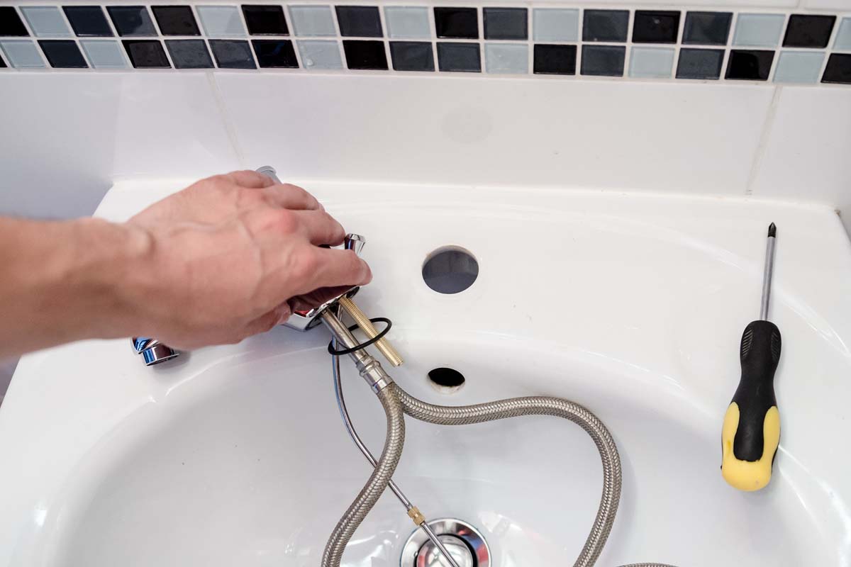 Handwerker baut neuen Wasserhahn und Mischbatterie ein